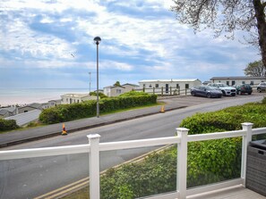 A coastal road with parked cars, a white fence, and a view of the beach. - Ivy Close 20 - UKC9401 (Exmouth)