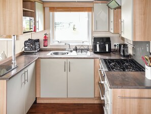 A compact kitchen with a sink, stove, and coffee maker. - Ivy Close 20 - UKC9401 (Exmouth)