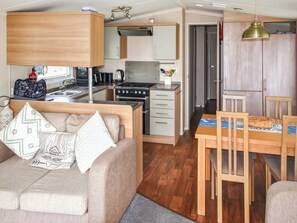 A compact living space with a kitchenette, a dining area, and a sofa with decorative pillows. - Ivy Close 20 - UKC9401 (Exmouth)