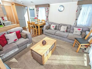Ein Wohnzimmer mit einer Couch, einem Couchtisch, einem Esstisch mit Stühlen und einer Wanduhr.