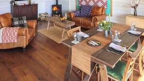 A cozy living room with a fireplace, leather sofas, a dining table set for two, and a television on the wall. - 2 bedroom accommodation in Cardiff (Cardiff)