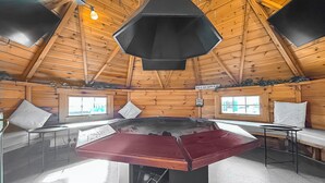 A wooden cabin with a central table, two windows, and a sign indicating a happy place. - Relax in our stunning seaside glamping pods in Peterhead. (Banff)