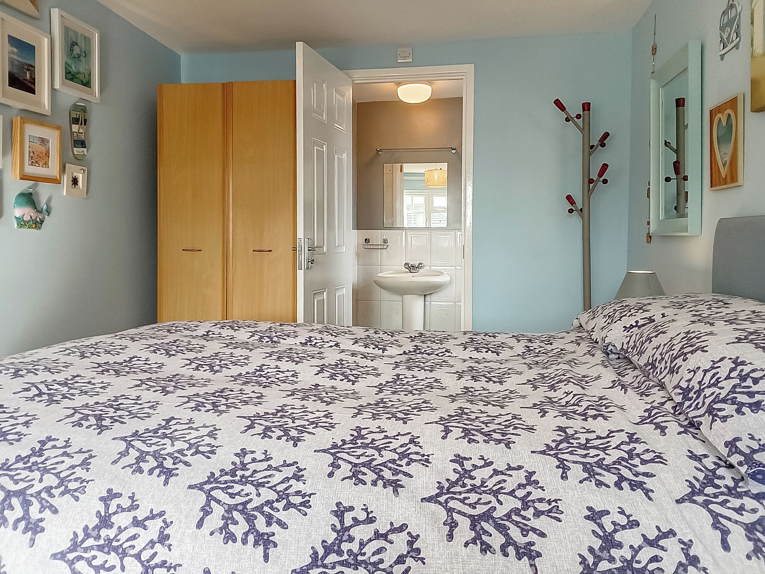 A bedroom with a bed, a wardrobe, a bathroom with a sink, and a mirror.