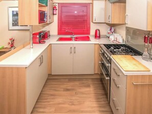 A compact kitchen with a sink, stove, and cabinets. - Hawks View 44 - UKC9399 (Exmouth)