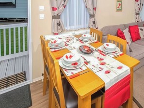 Ein Essbereich mit Tisch für vier Personen, Stühlen, einer Couch und Blick auf ein blaues Gebäude.