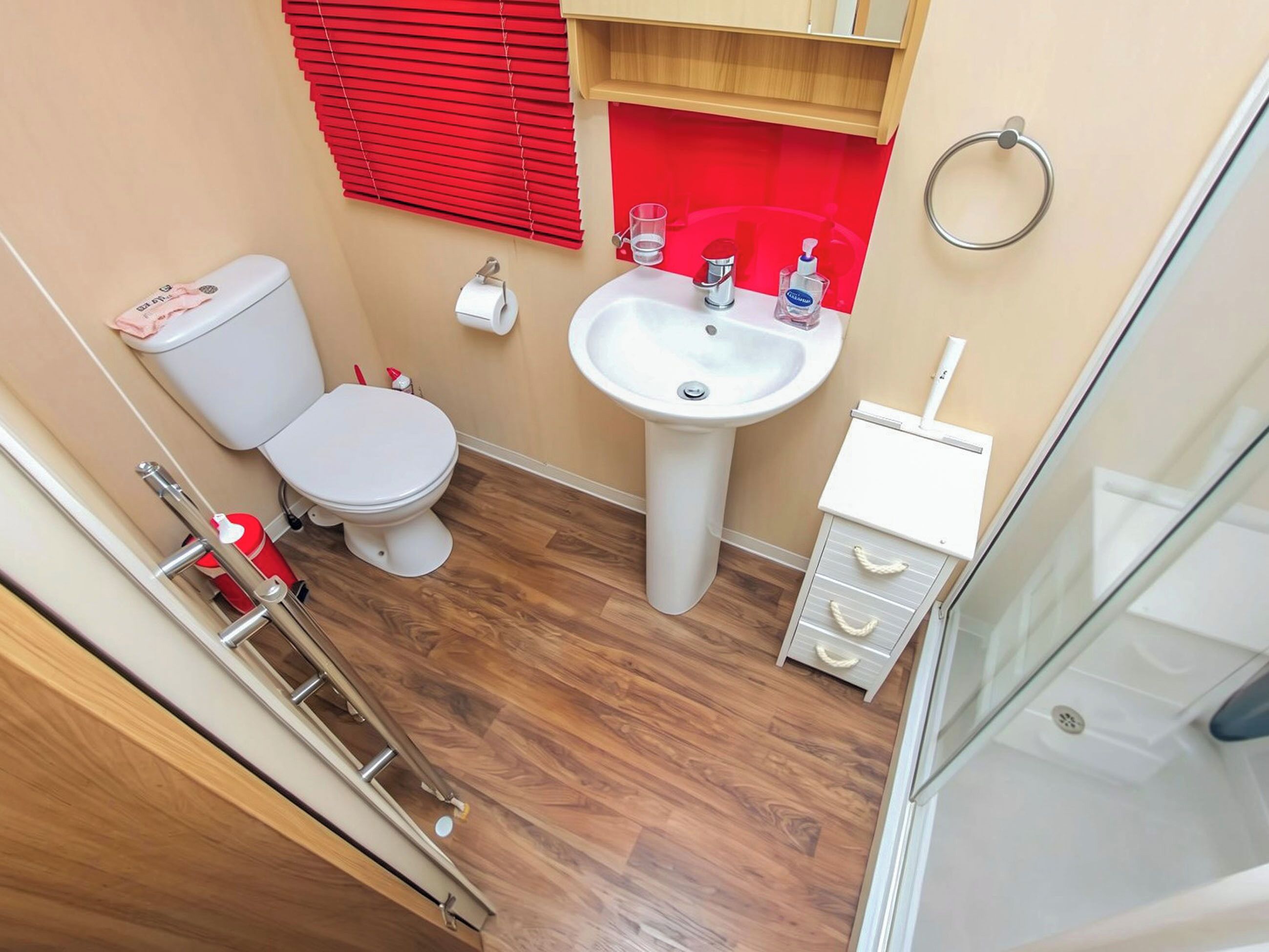 A compact bathroom with a toilet, sink, and storage cabinet.