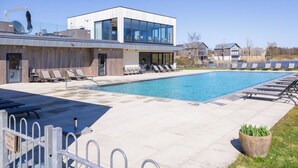 Ein modernes Gebäude mit Schwimmbad, Liegestühlen und blauem Himmel.