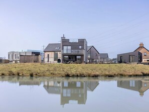 Ein modernes Haus mit großer Garage, Schwimmbad und einer Rasenfläche davor.