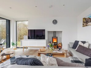 Ein modernes Wohnzimmer mit Kamin, Sofa, Couchtisch und Fernseher.