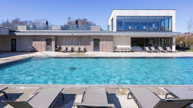 A modern building with a pool, lounge chairs, and a clear blue sky. - 3 bedroom accommodation in Dorchester (Dorchester)