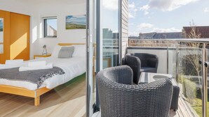 A modern bedroom with a large bed, a small bedside table, and a window. - 3 bedroom accommodation in Dorchester (Dorchester)