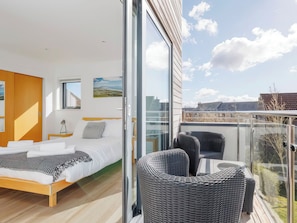 Ein modernes Schlafzimmer mit einem großen Bett, einem kleinen Nachttisch und einem Fenster.