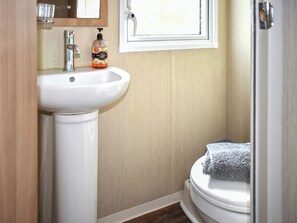 Ein Badezimmer mit einem weißen Waschbecken, einem Fenster und einer Toilette.