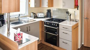 Eine kleine Küche mit Spüle, Toaster, Herd, Backofen und Schränken.
