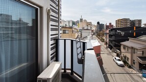Un balcón con vistas a un paisaje urbano, una ventana y una barandilla.