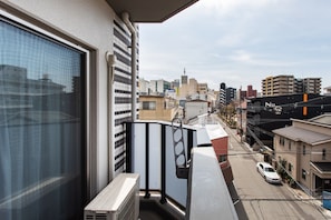 Ein Balkon mit Blick auf eine Stadtlandschaft, ein Fenster und eine Brüstung.