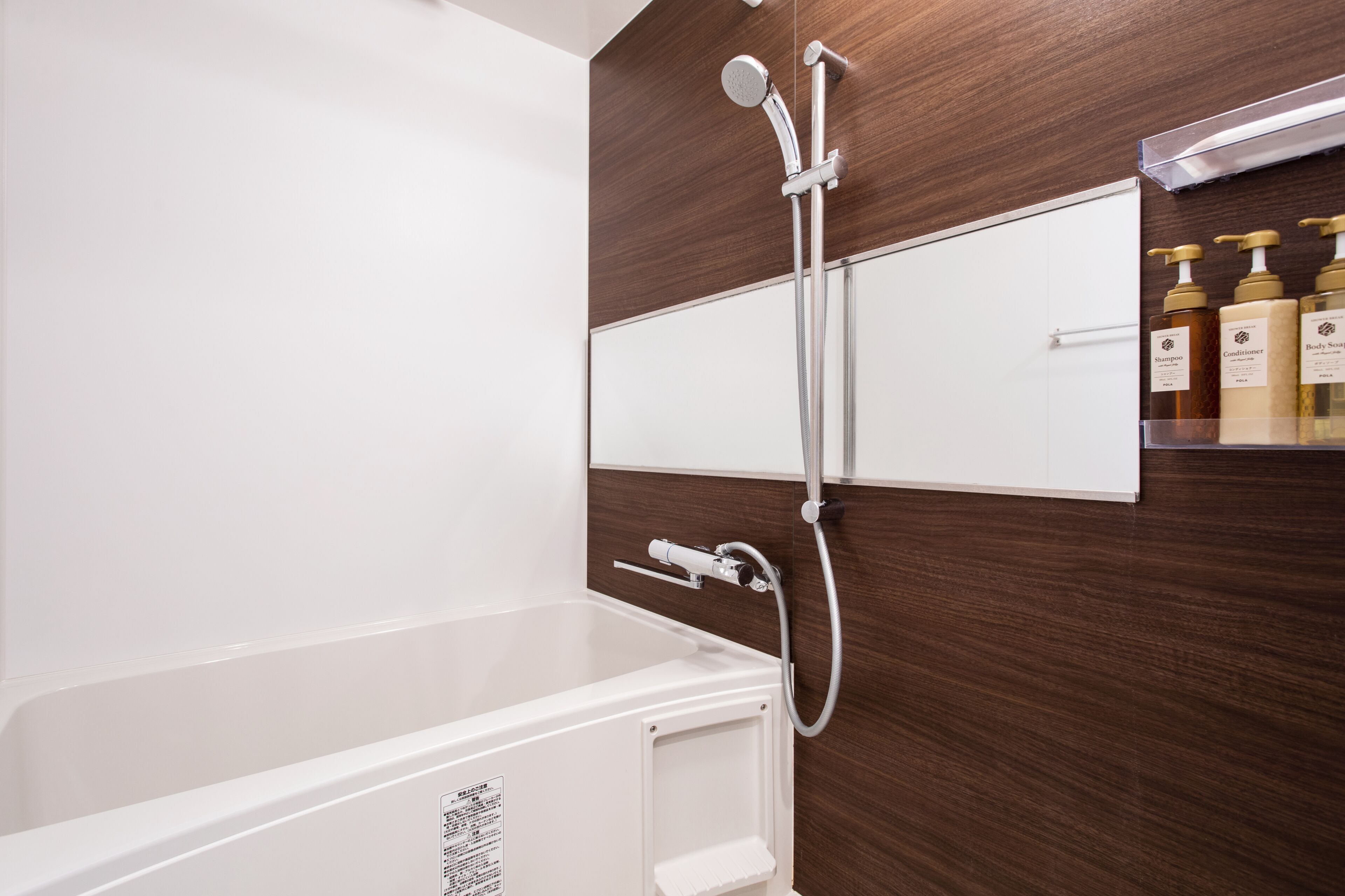 Un baño moderno con una bañera blanca, un panel de pared de madera y un estante con artículos de aseo.