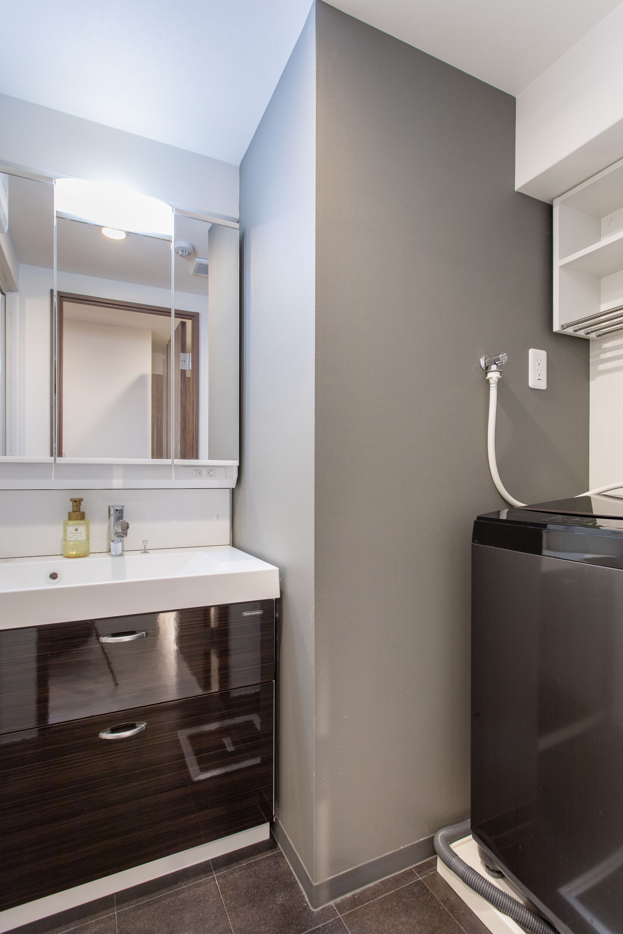 Une salle de bain moderne avec un lavabo blanc, un meuble-lavabo en bois foncé, un miroir et un espace douche.