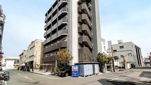 Un edificio de varios pisos con balcones, zona de estacionamiento y máquina expendedora.