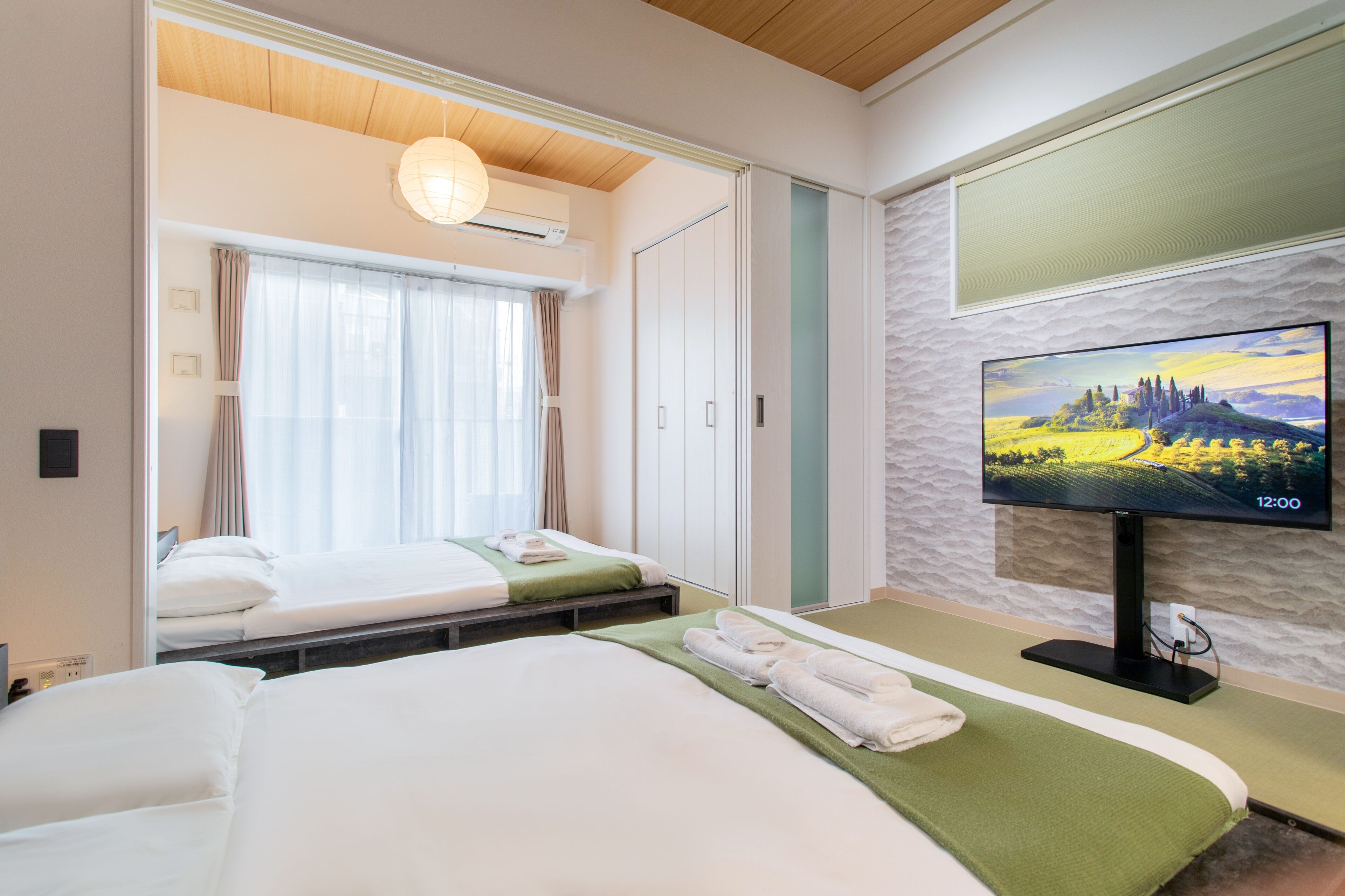Une chambre d’hôtel avec deux lits, une télévision et une fenêtre avec des rideaux.
