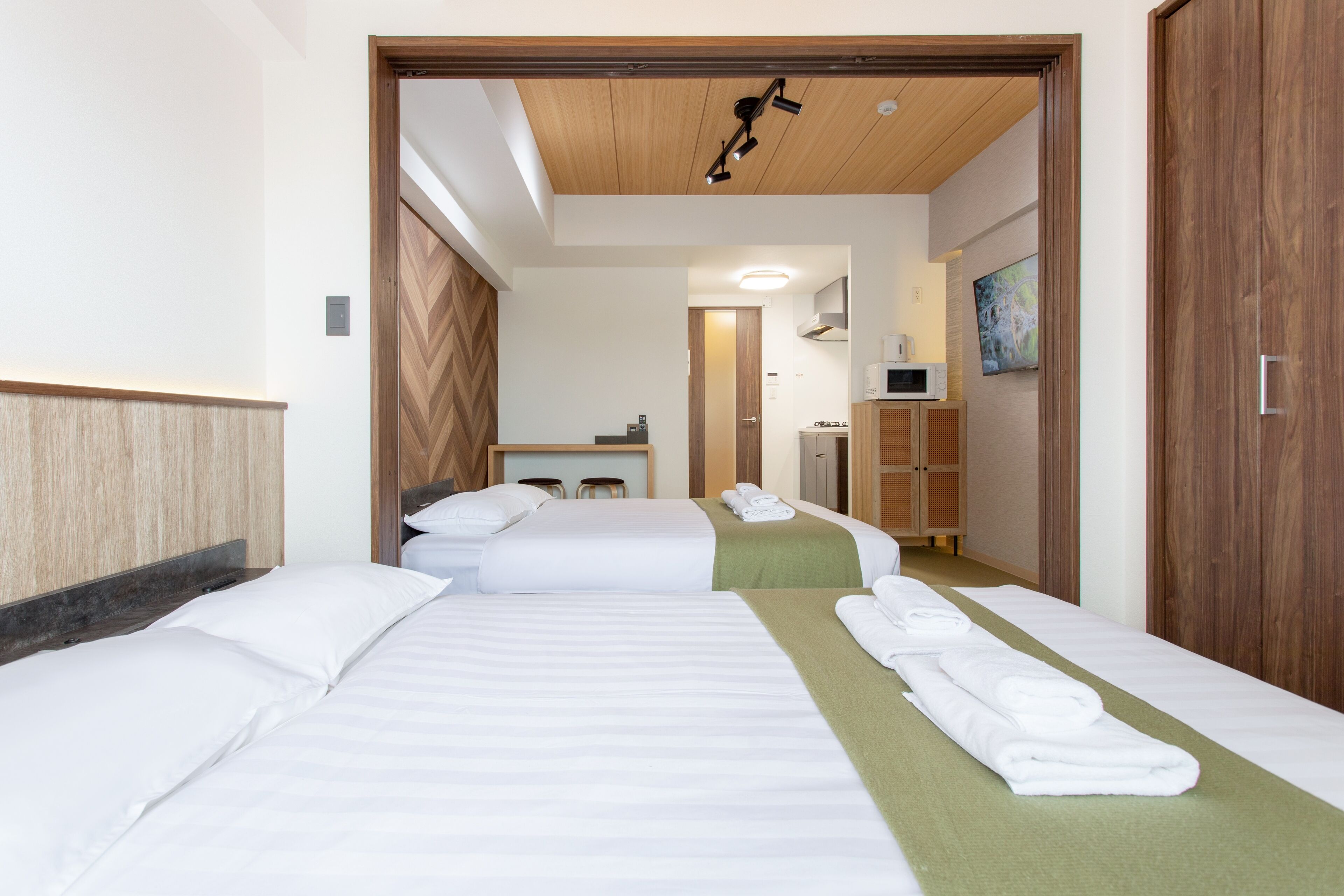 Habitación de hotel con tres camas, techo de madera, microondas y un cuadro en la pared.