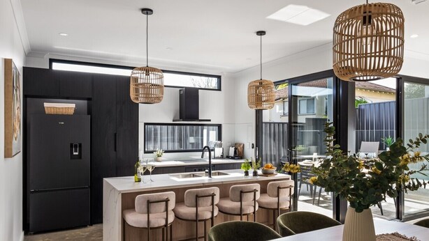 Una cocina moderna con una isla central, taburetes de bar e iluminación colgante.