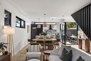 A modern interior with a dining area, sofa, and staircase. - Stone River Villa 3 | Relaxed Stay | Heated Pool (Margaret River)