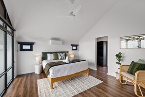 A modern bedroom with a wooden bed, a ceiling fan, a window, and a rattan chair. - Stone River Villa 3 | Relaxed Stay | Heated Pool (Margaret River)