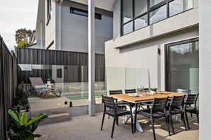 A modern outdoor patio with a dining table, chairs, and a pool. - Stone River Villa 3 | Relaxed Stay | Heated Pool (Margaret River)