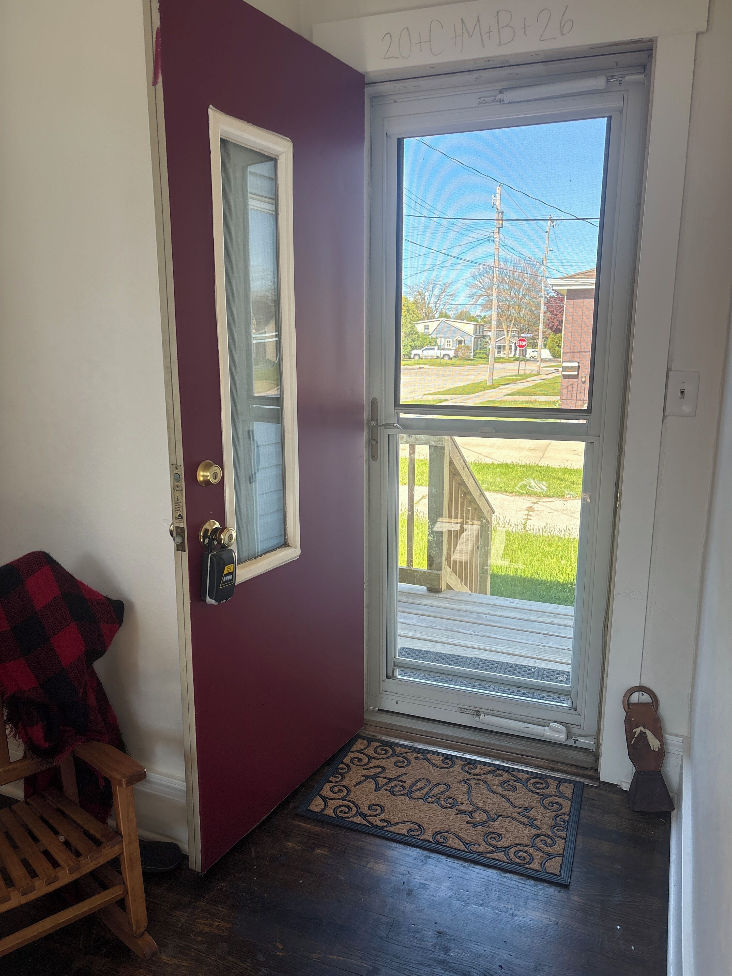 Une porte avec une fenêtre, un paillasson et un banc.