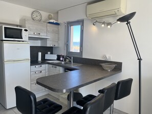 A compact kitchen with a microwave, refrigerator, sink, and a window. - Capitole, seafront, studio with sleeping alcove for 3 people, 26m2, balcony with partial sea view, air conditioning, private parking (Fréjus)
