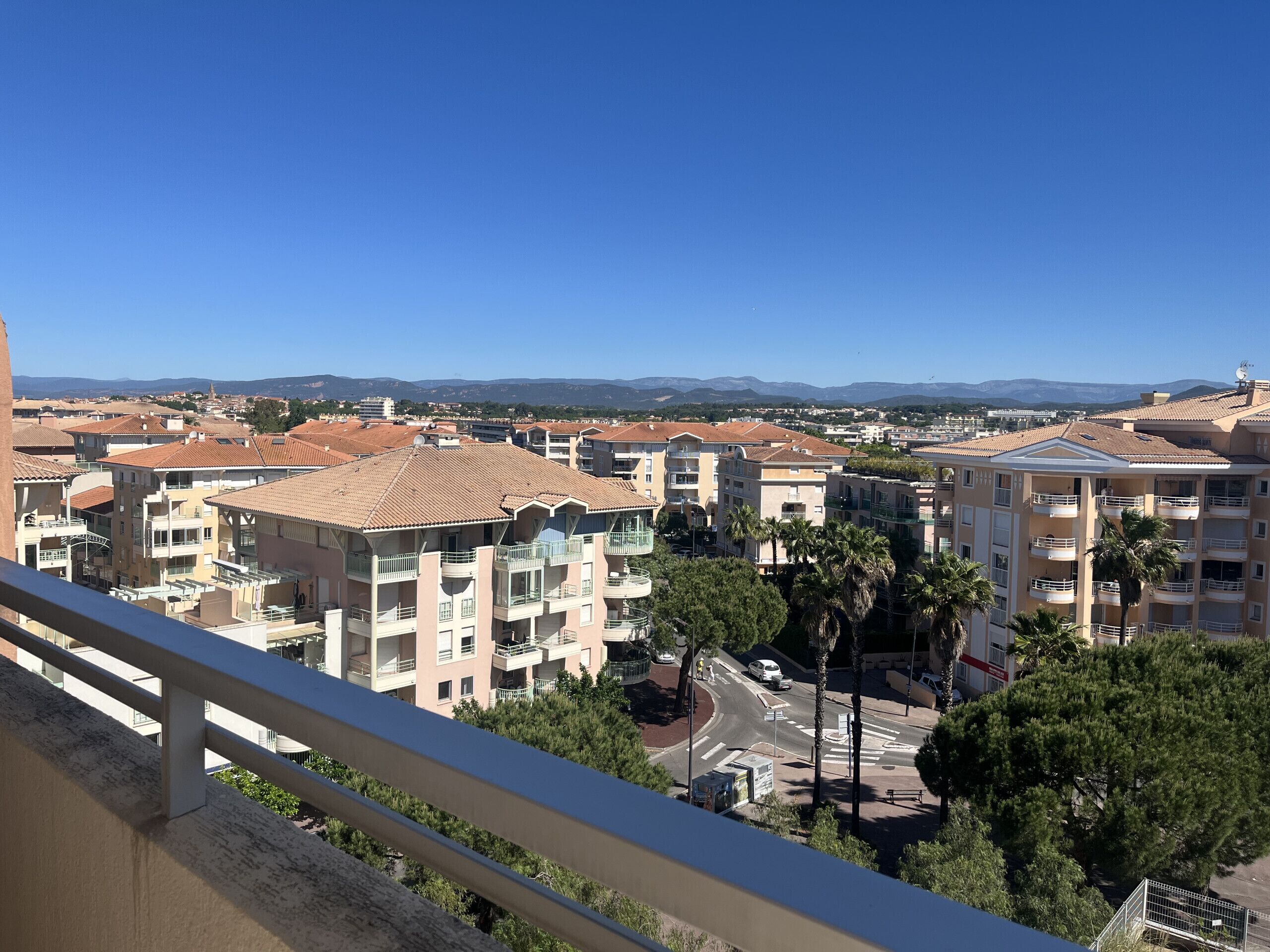 A residential area with multi-story buildings, balconies, and a clear sky.
