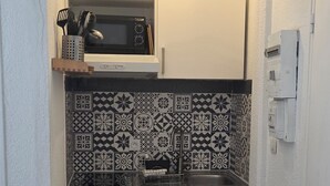 A compact kitchen with a microwave, sink, and dishwasher. - Charming studio in the heart of uriage (saint martin d'uriage)