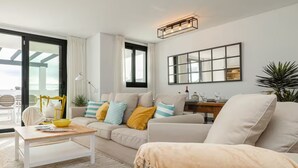 A modern living room with a sofa, coffee table, and a dining area with a table and chairs. - Solmare, Coastal Comfort in Estepona (Estepona)