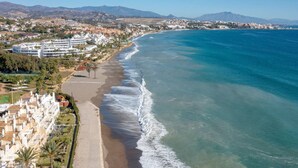 A coastal resort with beachfront villas, a sandy beach, and a view of the ocean and distant mountains. - Solmare, Coastal Comfort in Estepona (Estepona)
