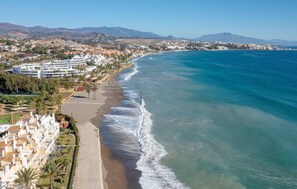 A coastal resort with beachfront villas, a sandy beach, and a view of the ocean and distant mountains. - Solmare, Coastal Comfort in Estepona (Estepona)