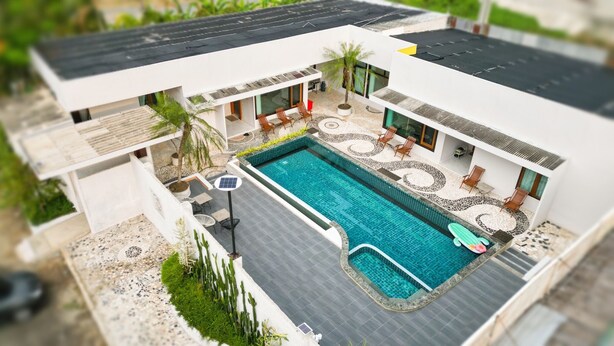 Ett modernt hus med en swimmingpool, utomhusmöbler och en solpanel.