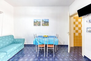 Ein kleiner Essbereich mit Tisch und Stühlen, einem Sofa und zwei Bildern an der Wand.