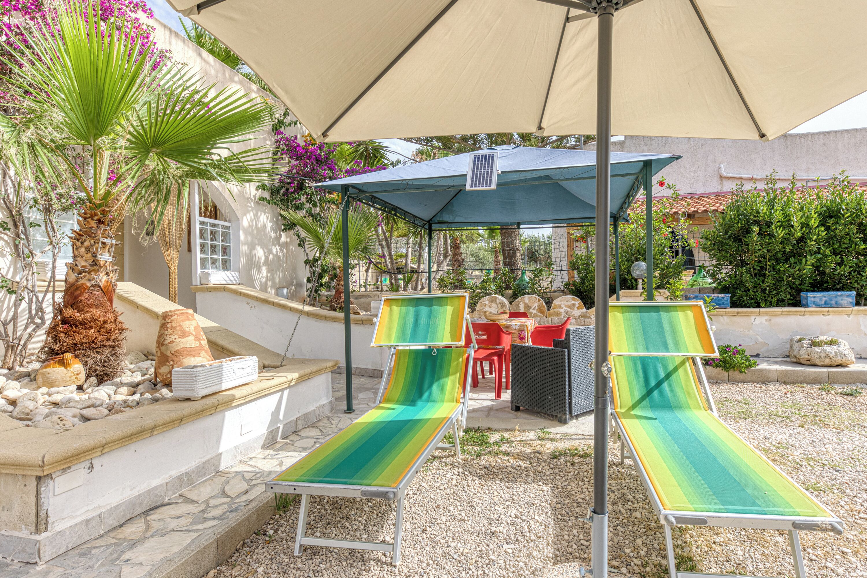 Un espace extérieur aménagé, abrité et doté de deux fauteuils, d’une table et d’une pergola.