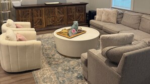 A living room with a flat-screen TV, a ceiling fan, a wooden cabinet, and a beige sofa.