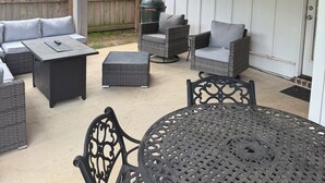 An outdoor patio with wicker furniture, a round metal table, and a ceiling fan.