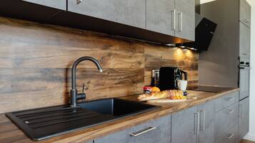 Eine moderne Küche mit einer Holz Arbeitsplatte, einem schwarzen Spülbecken und einem eingebauten Backofen.