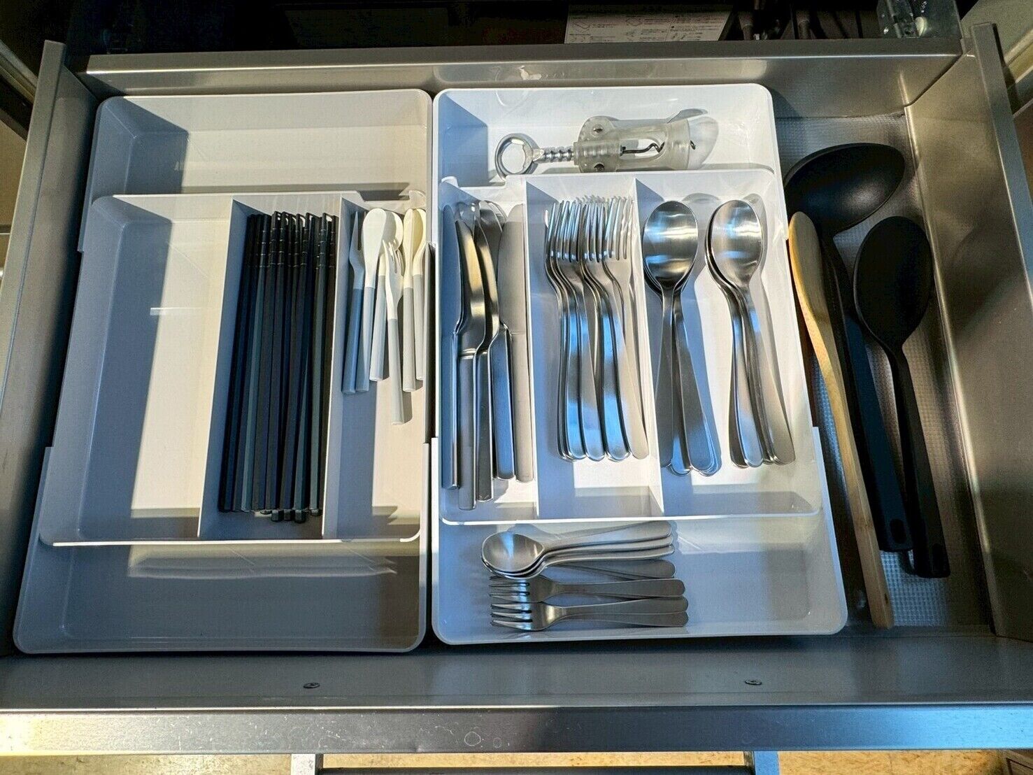 A drawer with neatly organized cutlery including forks, spoons, and knives.