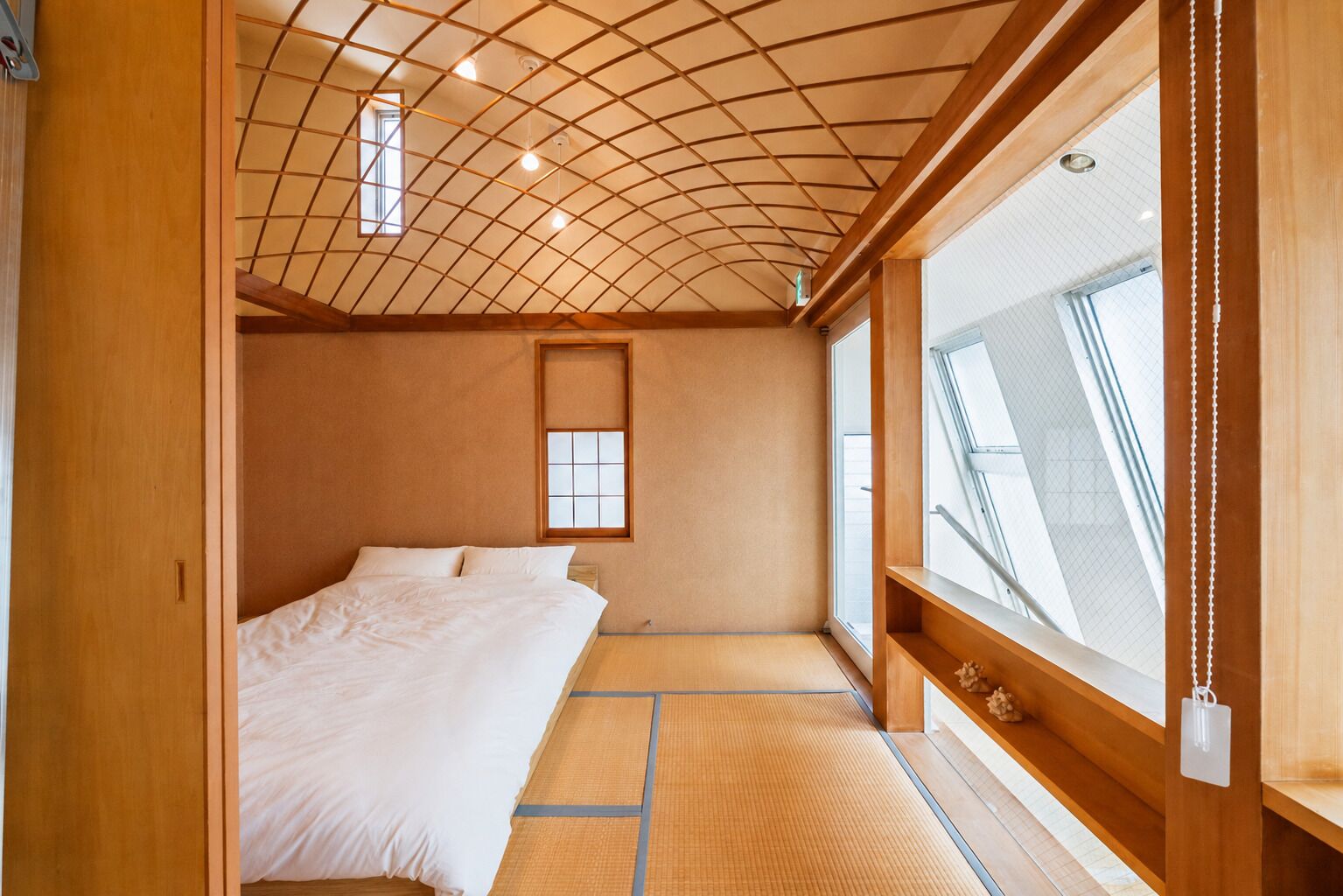 A room with a bed, a window, and a wooden ceiling.