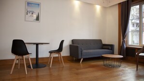Et moderne værelse med en grå sofa, to sorte stole, et rundt bord og et billede på væggen.
