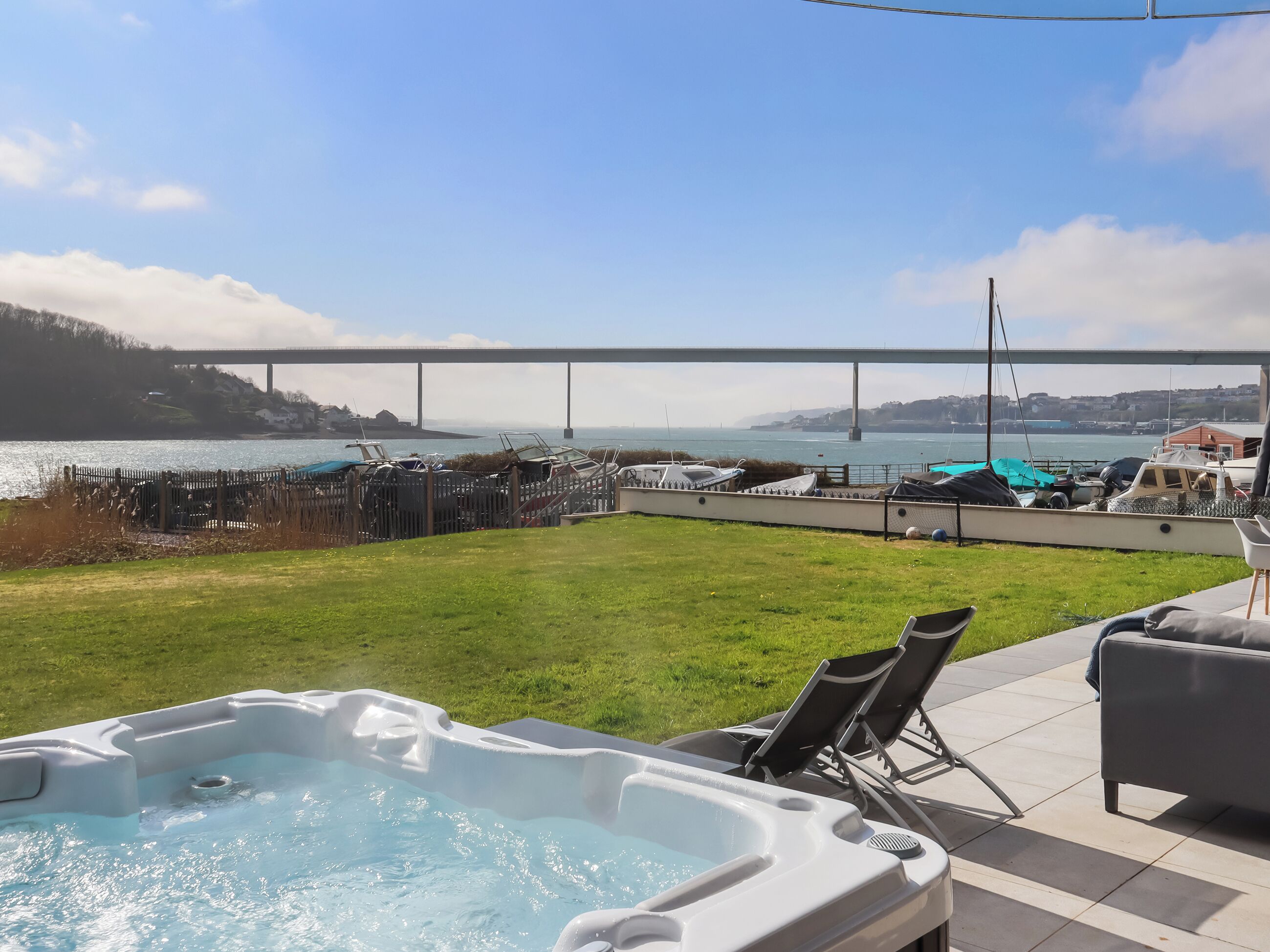 A hot tub with a view of a marina and a bridge.