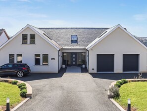 Ein modernes, zweistöckiges Haus mit Auffahrt, Garage und gepflegtem Rasen.