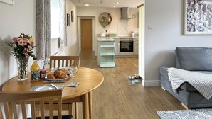 A dining area with a wooden table, chairs, and a vase of flowers. - Mawstone Mine Cottage (Youlgrave)