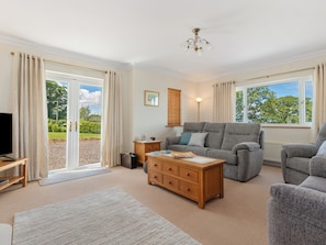 A living room with a sofa, armchair, wooden coffee table, and a television. - 4 bedroom accommodation in Narberth (Narberth)