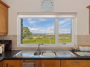 A kitchen with a large window, a sink, and a clock on the wall. - 4 bedroom accommodation in Narberth (Narberth)